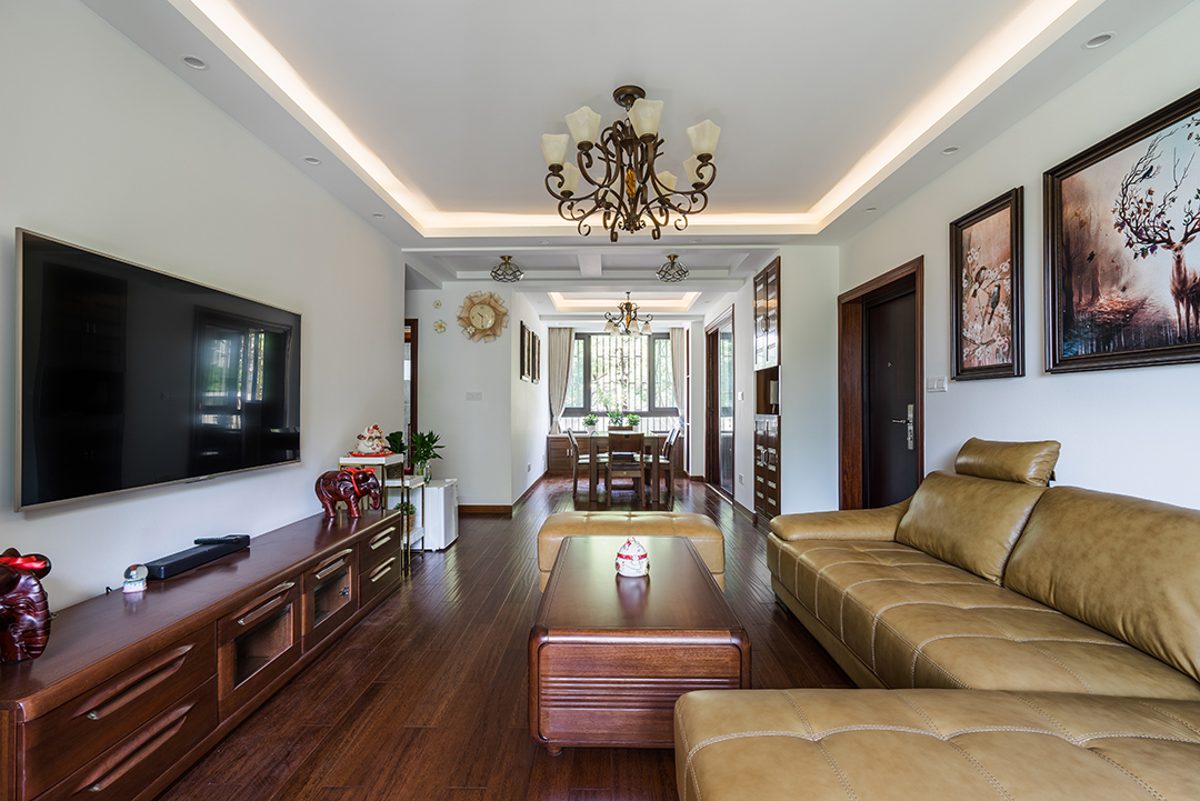 客廳新中式風格主要以厚重深色為主，當我們把客廳的主色調換成傳統的白色時，擺脫沉重，清新之氣撲面而來。但是在革新的基礎上還是要保留部分傳統的中式效果色，稍微的暗紅色地板、家具讓客廳在清新中帶著一份優雅，在淡雅中帶著對生活的一份執著。沙發背景墻上幾幅掛畫也是充分體現了中式元素的標志。紅色，中國傳統文化中不能丟失的顏色，也是定義中式的標志元素。