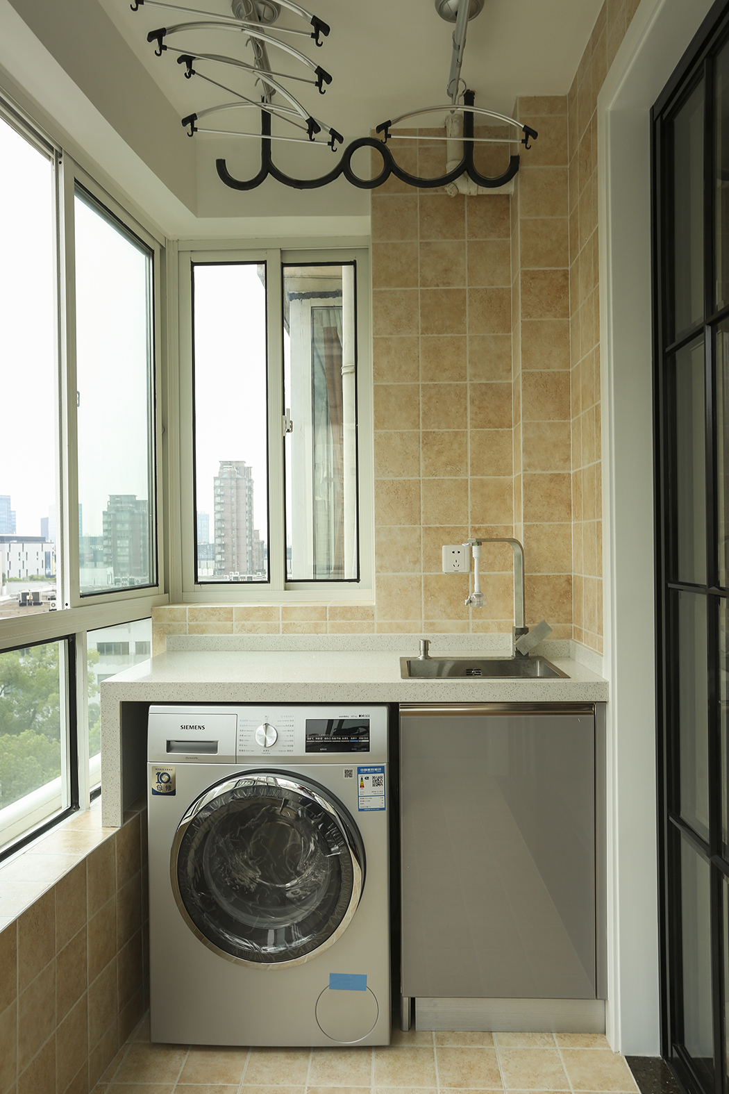 陽(yáng)臺(tái)的瓷磚選擇了仿古亞光面的感覺(jué)，讓陽(yáng)臺(tái)成為了一個(gè)休閑工作的空間，定制的洗衣機(jī)一體柜讓空間擺放更加的合情合理。
