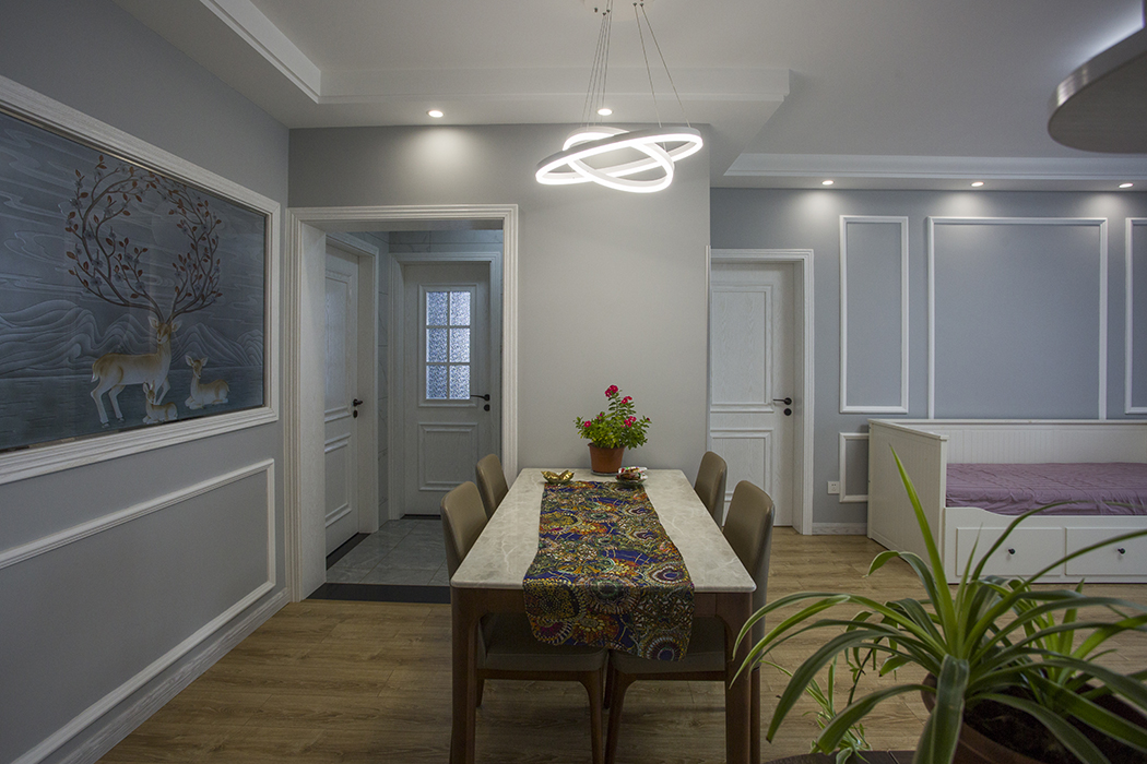 餐廳左邊，一個影響的背景墻。原本是餐廳，后來新建了一個小房間，因為小房間光線不好，做了磨砂的玻璃，再配上一個精致的小鹿和簡單的石膏線搭配在一起，增加了餐廳的時尚原色。餐桌上配了一快帶有名族風的桌布，在簡單的灰色系里，讓家里的顏色更活躍，給客廳和餐廳做了一定的點綴。
