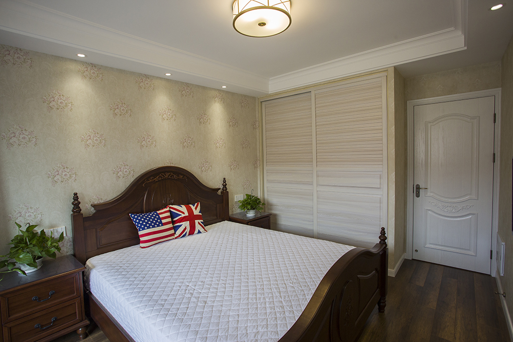 主臥室采用美式素色墻紙和淺色衣柜搭配，整個房間以深色為主體，將美式色彩應用發揮的淋淋盡致，伴有美式風格。深色美式實木床，展現軟飾的搭配，體現業主的追求穩住自由的生活。
