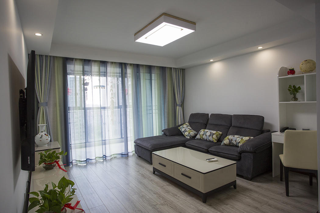 客廳耀眼的灰色沙發(fā)，是主人精心挑選的顏色。配上精致的玻璃燈和線簾的裝飾，把板式的硬線條做了軟性富有穩(wěn)重
