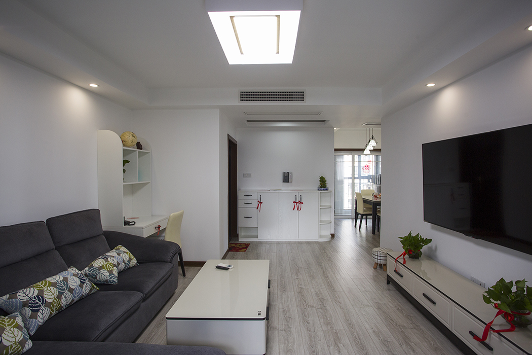 一進門就覺得客廳很大氣，沒有任何累贅的裝飾和家具，耿沒有一絲空蕩感，主要是設計師在材質(zhì)和墻面裝飾上下了心思。電視背景墻無任何裝飾點綴，加上燈光的豐富視覺，構(gòu)成了一個大氣簡單卻又溫暖的客廳空間。
