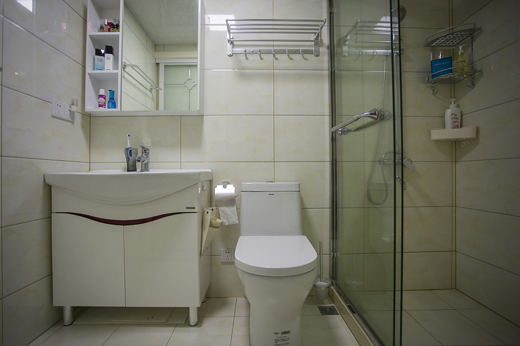 縮小面積之后的衛生間剛剛好擺放臺盆、坐便器、淋浴間“三大件”，明亮整潔。門洞改到中間后，避免了直對進戶門的“門沖”。
