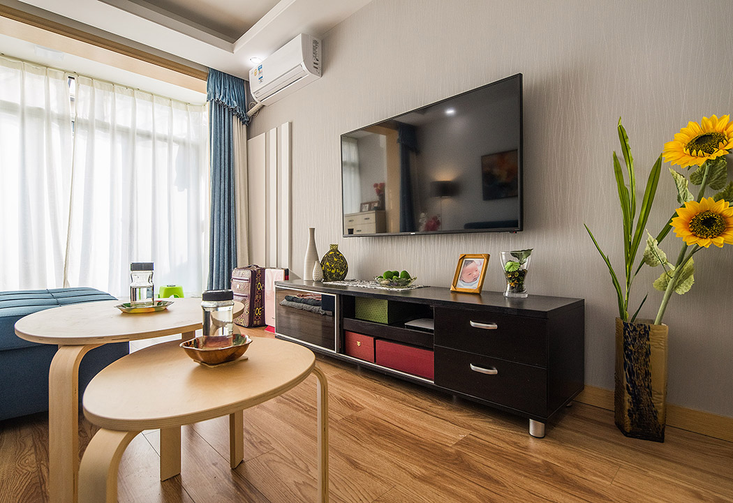 客廳空間內以原木色的地板和米白色的墻紙主色調，色明快的軟裝及家具設定，做了有趣的色彩撞擊，生動玩味，白色的定制柜及木飾面豐富了整體材質，在輕奢主義的格調里融入一些原生態的溫馨舒適且隨意自然的風情。
