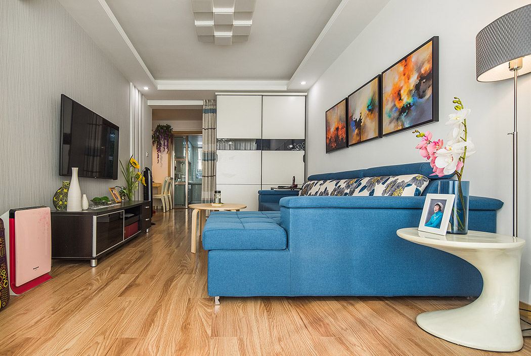 客廳空間內以原木色的地板和米白色的墻紙主色調，色明快的軟裝及家具設定，做了有趣的色彩撞擊，生動玩味，白色的定制柜及木飾面豐富了整體材質，在輕奢主義的格調里融入一些原生態的溫馨舒適且隨意自然的風情。
