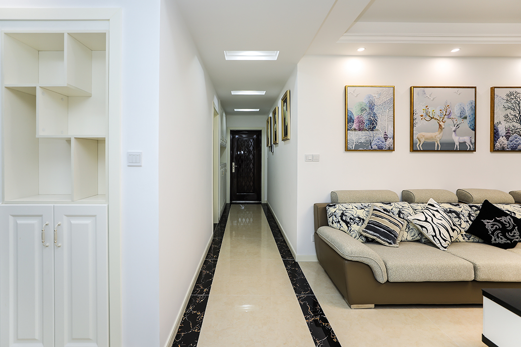 走道米黃色玻化磚四周配上黑金花走邊，大氣而不單調，時尚而不簡單。進門玄關處大鞋柜滿足了主人的收納空間和實用功能。三幅大小一致的裝飾畫，把深長的走道點綴地完美無瑕。
