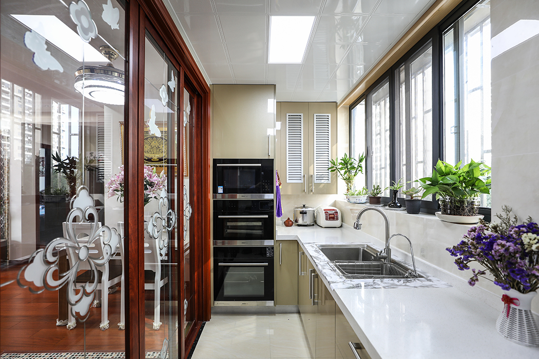 廚房間的設計風格并沒有沿用整體的新中式的理念，而是采用了更加直接實用的亞克力作為主體，簡約的同時又便于打理。白色的瓷磚搭配香檳色的櫥柜，凸顯了更多的層次。
