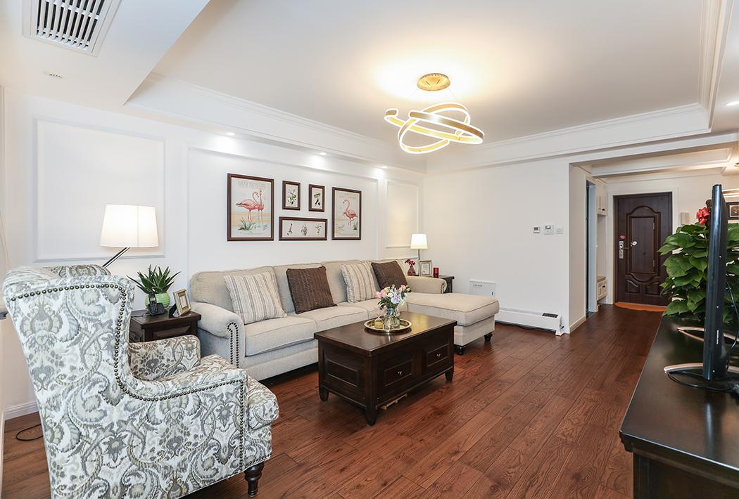 沙發(fā)后簡約的線條搭配布藝沙發(fā)顯得簡約而不復(fù)雜，條線采用對稱的手法，布藝沙發(fā)搭配實木茶幾，2側(cè)的茶幾，都在凸顯出現(xiàn)代美式的格調(diào)。
