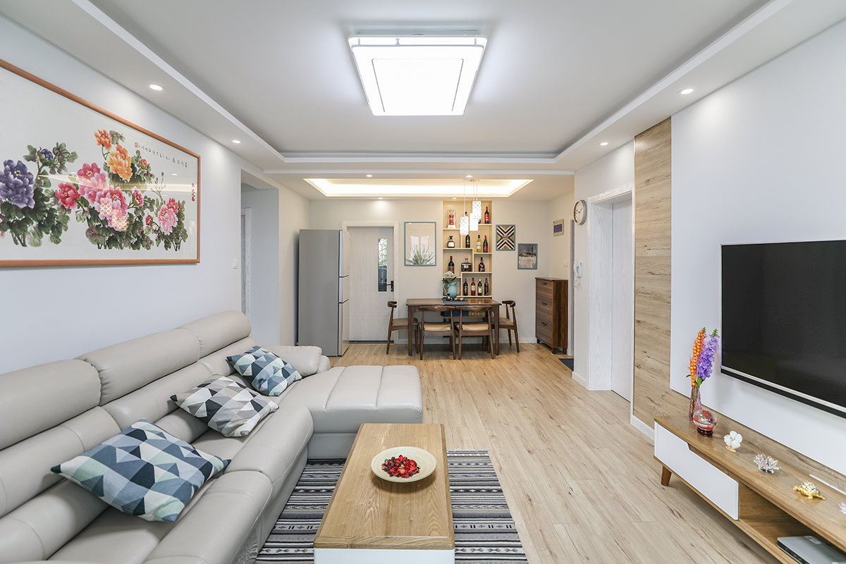 客廳區，電視背景連接地面整體采用同款地板，視覺上得到延伸，整體則由淺灰色構簡潔背景，并添入不少具生活質感的軟裝，交織出兼具美觀，舒適的質感視野。
