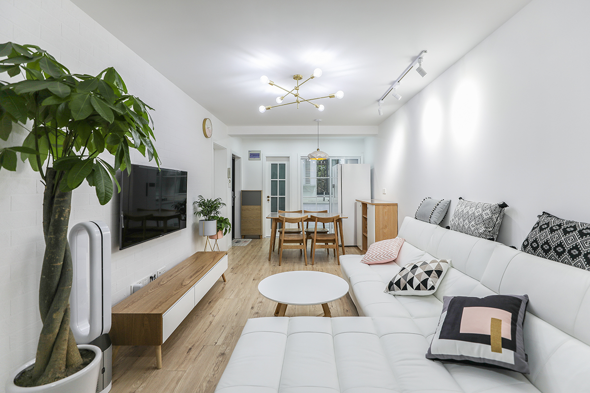 該套房客廳是由原來的臥室改造而成，光線不太明亮，所以整體以白色為主，配上淺色作舊地板和金色吊燈，使空間干凈清爽、豐富多彩，不單一吊板。
