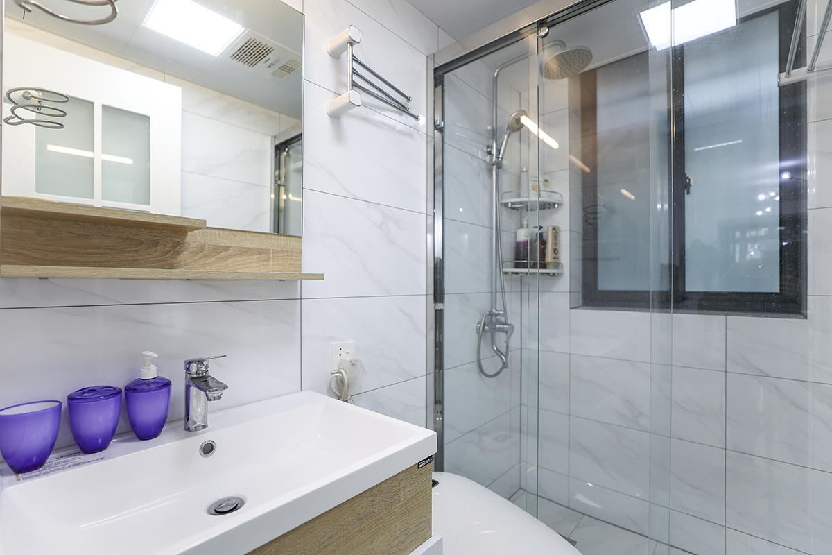 衛生間以實用為主，一般分為三大功能區，盥洗區、廁所區、浴室區。盥洗在前，廁所居中，浴室在后。該空間各大功能區布置的井井有條，色調上白色的潔具、白色的瓷地磚配上暖色調的實木浴室柜，使衛生間既干凈又溫馨。