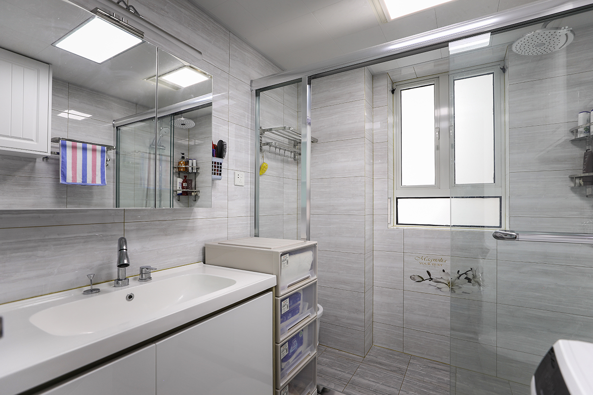 白色總是可以讓人的心情放松，小戶型的衛(wèi)生間淡灰色色的瓷磚，可以讓空間看起來寬闊明亮，空間大了，心自然就開闊了。淋浴房用玻璃隔斷起來，不僅增加整個衛(wèi)生間的美感，同時防止衣服被沐浴的水打濕。
