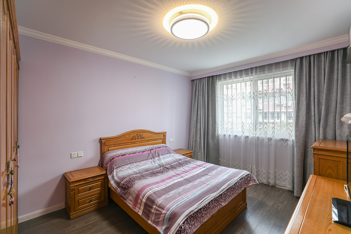 主臥采用了跟客餐廳呼應(yīng)的木色家具配置，顏色統(tǒng)一的木色衣柜，木色床及床頭柜，電視柜，跟墻面的紫色形成色彩上的對比色，讓空間更有層次。
