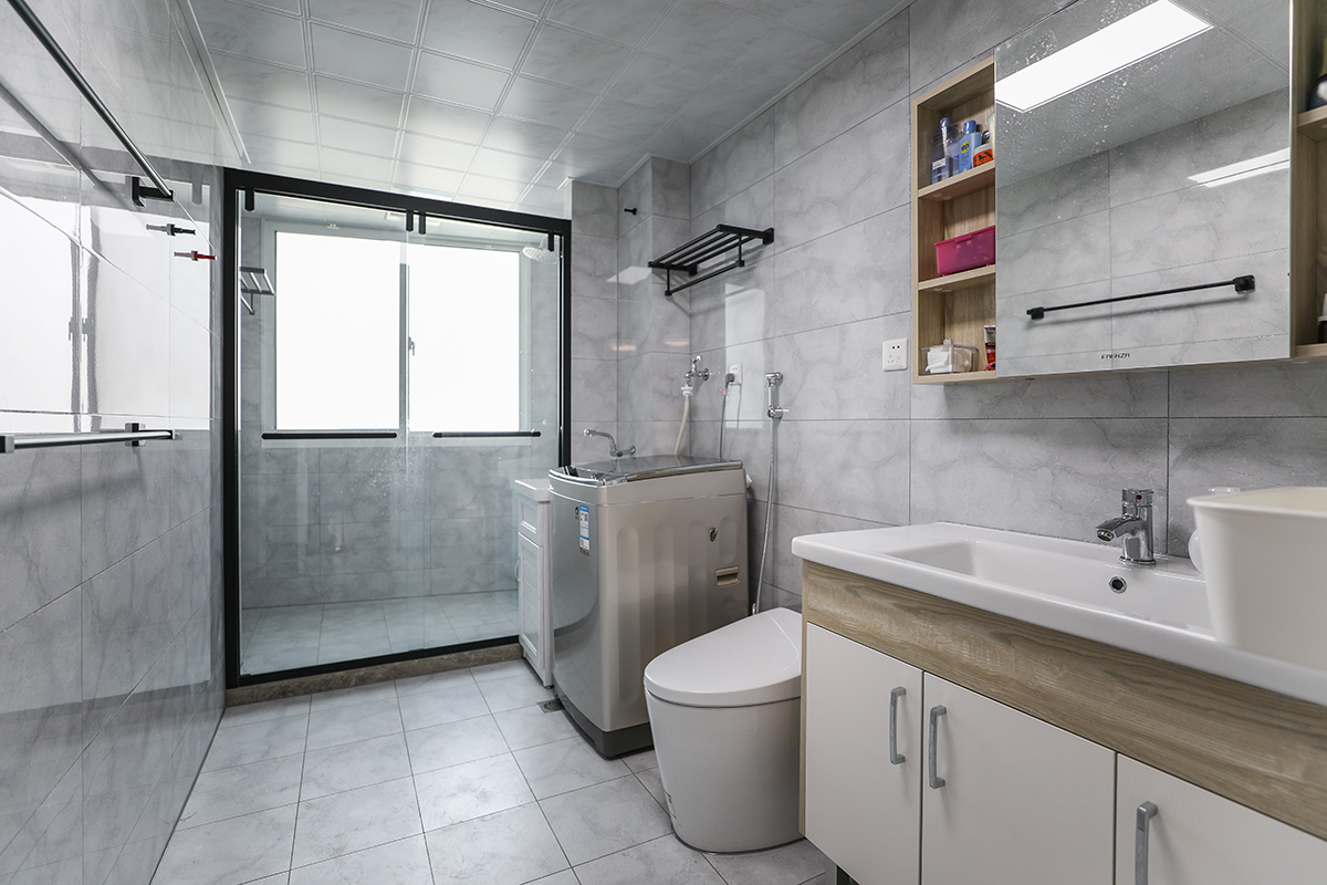 衛(wèi)生間淡灰色的瓷磚搭配木色的臺盆柜，讓空間顯的不是那么的“冷”。一體式馬桶的使用，既美觀又實用。
