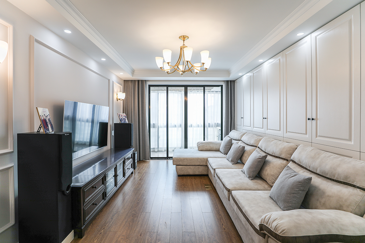 電視背景墻采用石膏線條，簡潔明快，現代風格的布藝沙發背后是一排白色儲物柜，極大的增加了收納空間。
