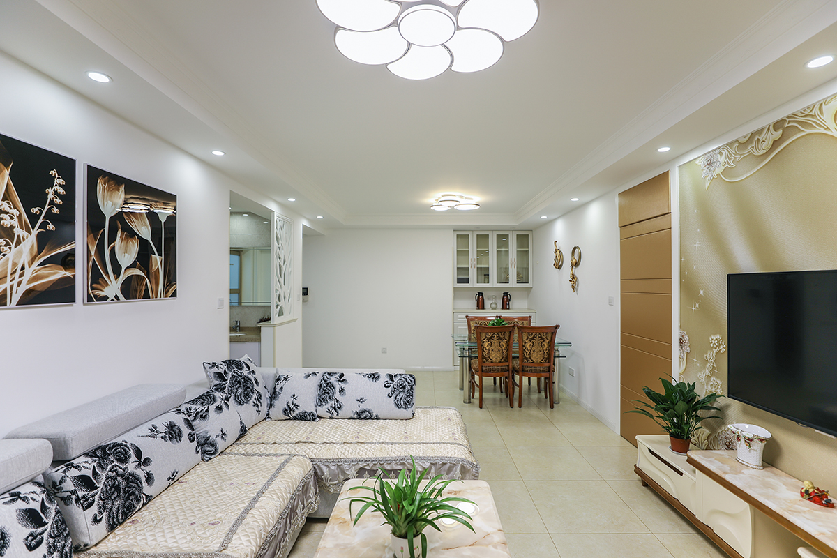 客廳背景墻的設計采用硬包墻紙的造型作為設計方案，巧妙的用硬包做成一扇隱形門，讓整個空間整體又大方，地面淺色地磚干凈清爽。
