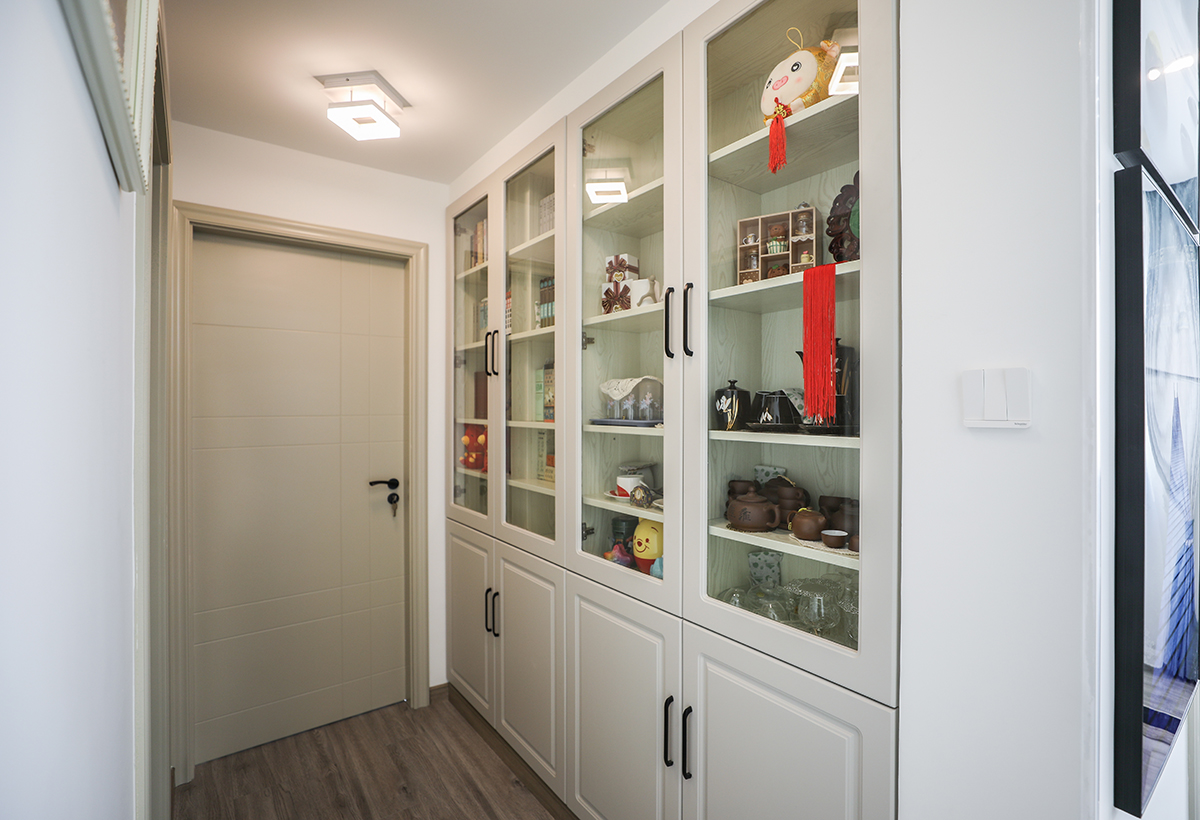 過道儲物門板上柜玻璃使得原本狹窄的過道更有深度，不僅起到了隔斷的作用同時(shí)讓空間有足夠的儲物及展示空間。
