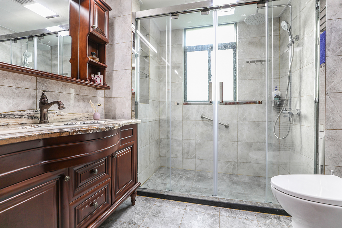 衛生間采用灰色系墻地磚，實木臺盆柜相得益彰。凸顯業主的品位。