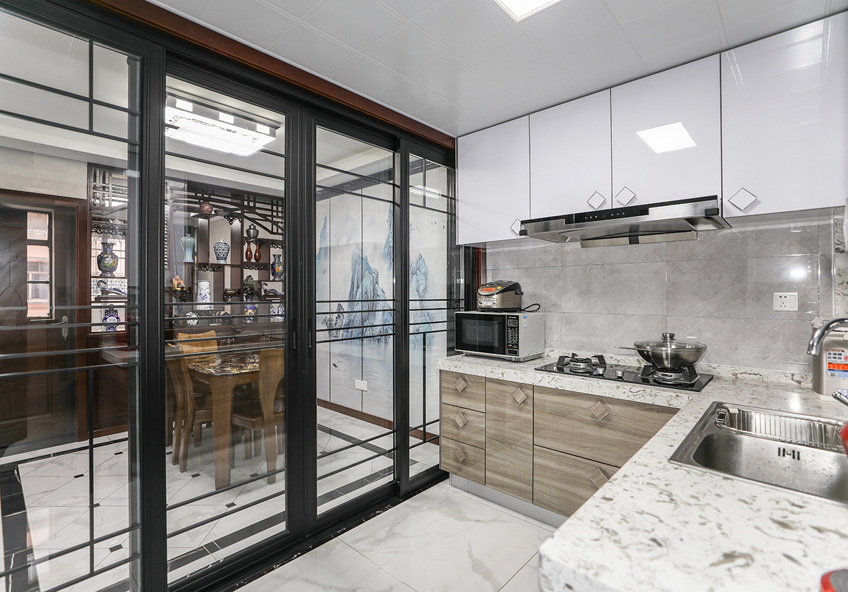 廚房磚面選擇了墻深地淺的磚面做背景，顛覆裝修的地深墻淺的傳統的概念同時，給與了廚房充分的采光的同時，呼應了櫥柜的下深上淺，色彩變換的同時增加了空間的層次感，廚房間四扇移門兩兩對應，呼應了中式中不變固有的對稱同時將陽光引入了室內.
