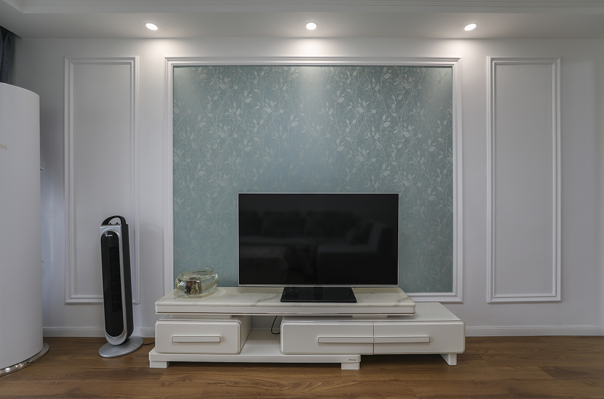 該套房客廳是由原來(lái)的臥室改造而成，光線不太明亮，所以整體以白色為主，配上灰色的沙發(fā)，現(xiàn)代時(shí)尚的吸頂燈，使空間干凈清爽、豐富多彩，不單一呆板。
