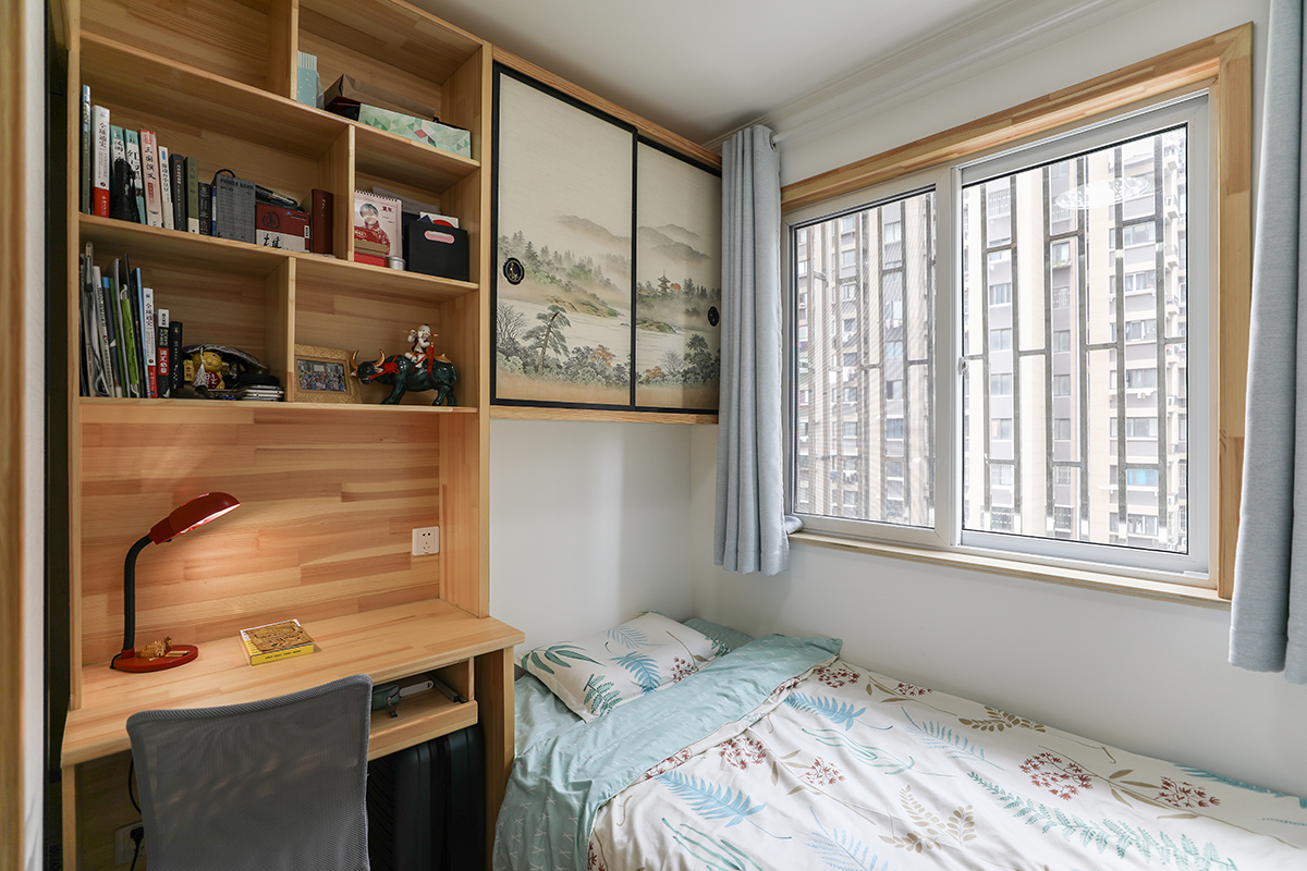 書房去蕪存真，減去一切不必要的裝飾，原木色一體書架和書桌干凈簡潔盡顯穩重，還原寧靜的閱讀學習空間。旁邊安置的單人床陳設簡潔，素色床品，在辦公學習累了臨時休息，亦可作為臨時客房。還有裝飾畫推拉板后的隱藏收納，融合在空間里，窗外明凈的陽光撒入屋內，寧靜暢然，點點滴滴保留生活的原汁原味。
