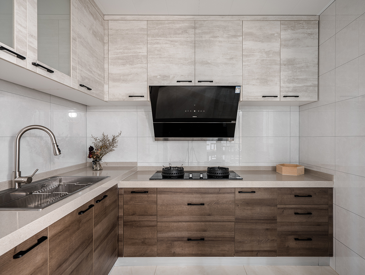 廚房空間沒有過多的去修飾，簡(jiǎn)單明了。深色的木紋櫥柜面版穩(wěn)重而內(nèi)斂。階梯式的臺(tái)面設(shè)計(jì)更好符合人體工程學(xué)。
