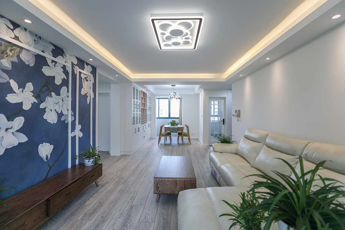 客廳沿用了當下比較流行的黑白灰的調調，墻面大面積的淡灰的顏色讓整個家里簡潔但不死板，空間的合理規劃，儲物的增加運用，讓女主人不用再為儲物而煩惱。背景墻的設計使用了客戶心儀的一抹藍色，讓整個空間生動又活潑。
