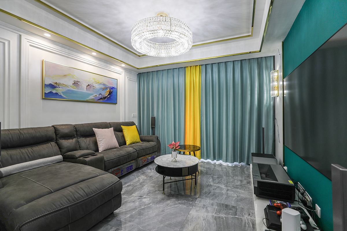 客廳整體風(fēng)格采用木，鏡，沙風(fēng)格，是當(dāng)下比較時尚也是板式的處理方式，在顏色上做了調(diào)色，配上精致的玻璃燈和線簾的裝飾，把板式的硬線條做了軟性富有穩(wěn)重。黑色的皮沙發(fā)，配上灰色的地磚，有層次感的護墻板，更彰顯出了整體的效果。電視背景墻，采用輕奢通用的爵士白上墻，再配上不銹鋼線條，中間是墨綠色的墻紙，細節(jié)附金色系裝飾點綴，時尚大氣。客廳的茶幾和電視背景墻的大理石相呼應(yīng)，茶幾側(cè)面的鏡色玻璃和茶幾的金屬線條。窗簾上的檸檬黃，和沙發(fā)上的檸檬黃抱枕相呼應(yīng)。客廳頂上的水晶燈，配上輕奢的金屬鋼線條搭在一起，使家里輕奢的效果更沉穩(wěn)。紅色的綠植在灰、綠、金屬鋼線條之前，作為點綴。
