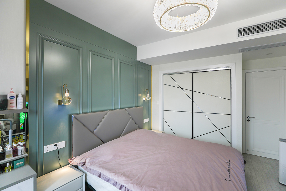    主臥背景采用墨綠色的護墻板，邊框帶有不銹鋼條，配有兩個水晶小掛壁式燈，主臥的衣帽間移門也是采用的效果明顯的金屬線條，配上米色的墻面，灰色的地板，灰色的床頭背景墻使得整個臥室很時尚、穩(wěn)重，又不奢華，客戶很滿意，
