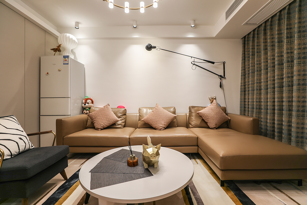 整個客廳采用了木色的地板，使得空間非常的簡潔清爽，造型的無意中給客廳增添一處亮點，暖色的墻面和木紋的地板加以白色的木門使得簡約元素非常的充足，得以空間的最大化。
