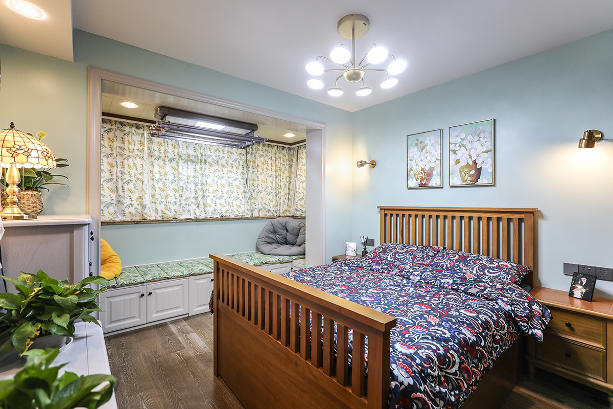 主臥背景色以淺藍色為主，選用純實木家具，陽臺做了卡座處理，會客儲物一應俱全。整體配色比較清爽。
