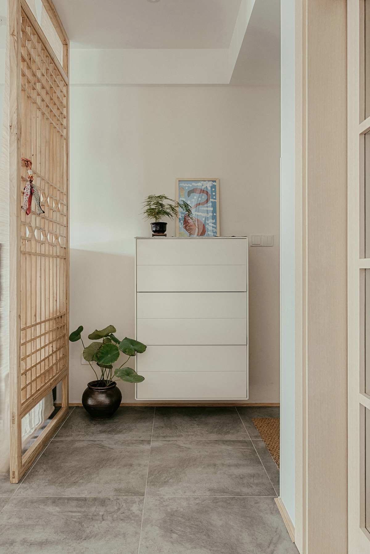 進門玄關空間略小，除了懸掛式鞋柜外，把空間分配做了隔斷，進門后并不會一眼望穿整個空間。鏤空隔斷在增強隱私性的同時又舒緩了視野，隔斷背后放置一架黑色的鋼琴，注重生活品質的業主，更喜歡平時練練鋼琴看看書，認真地思考生活的每一個細節，增添了生活的儀式感。
