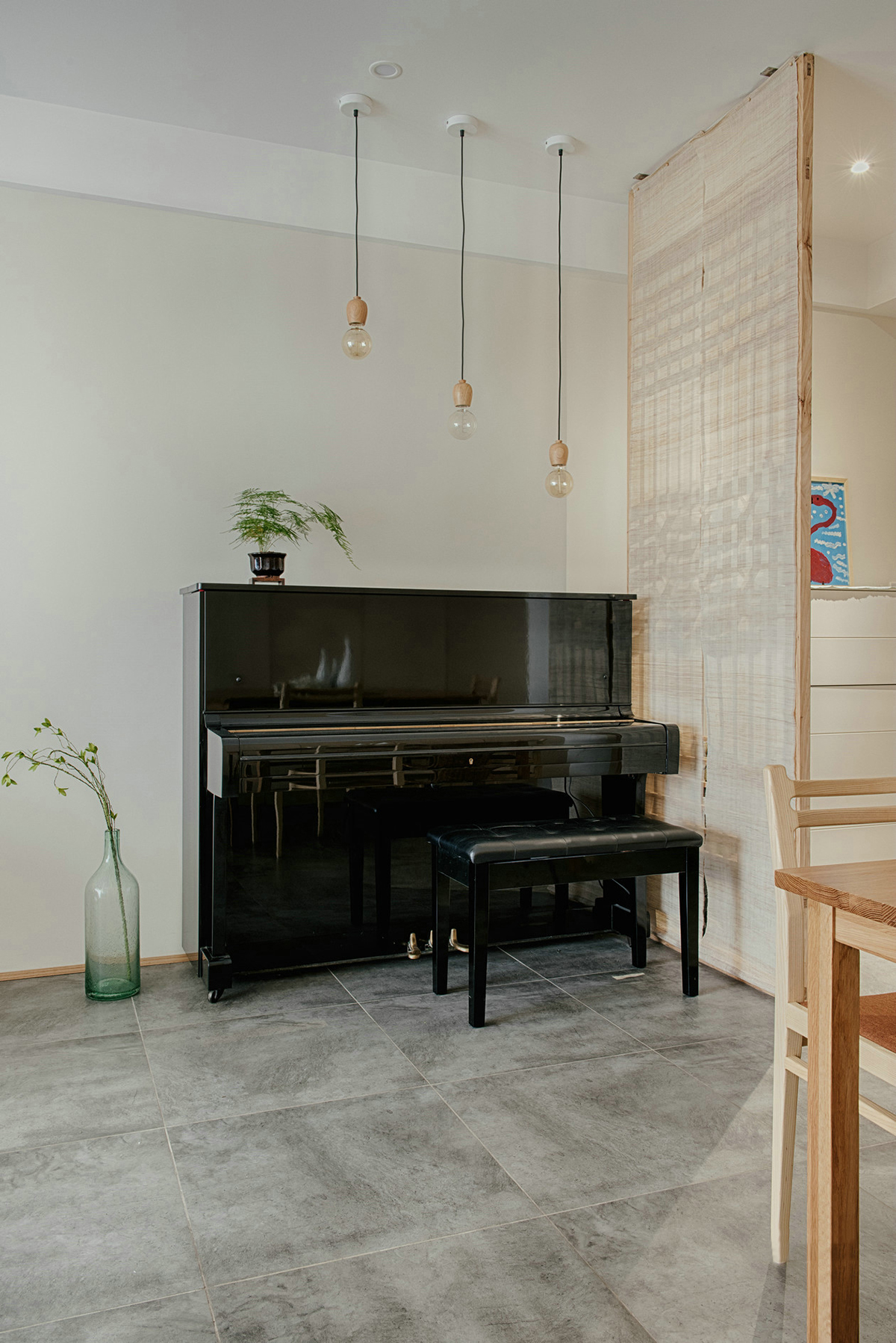 進門玄關空間略小，除了懸掛式鞋柜外，把空間分配做了隔斷，進門后并不會一眼望穿整個空間。鏤空隔斷在增強隱私性的同時又舒緩了視野，隔斷背后放置一架黑色的鋼琴，注重生活品質的業主，更喜歡平時練練鋼琴看看書，認真地思考生活的每一個細節，增添了生活的儀式感。
