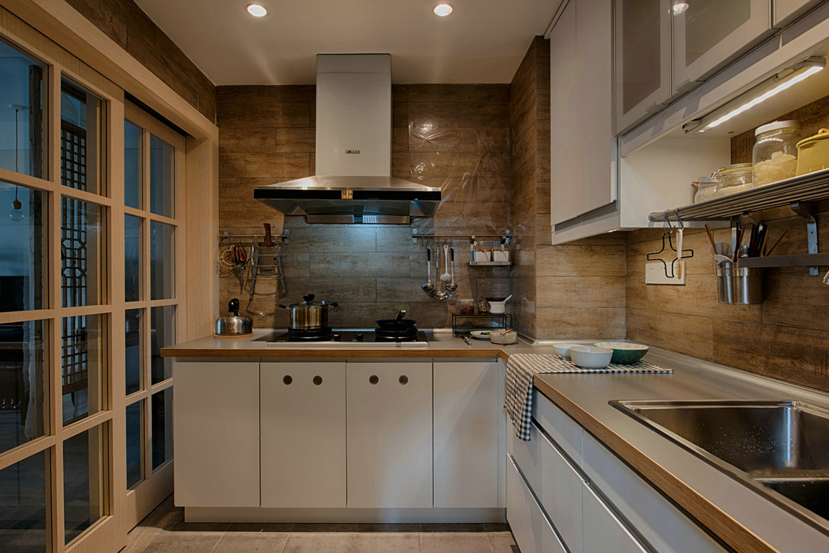 廚房清新雅致，追求整潔和舒適。不銹鋼臺面，低調不張揚，干凈明亮。深木色系墻磚，原木的韻味，讓廚房也能散發出自然氣息。業主愛旅游、愛收藏、愛養花弄草，因此在空間利用中，設計師為他們打造了一間多功能茶室，原木的小桌子，擺放著精致的茶具，讓他們在這里喝茶、看書、賞花，享受閑暇時光。
