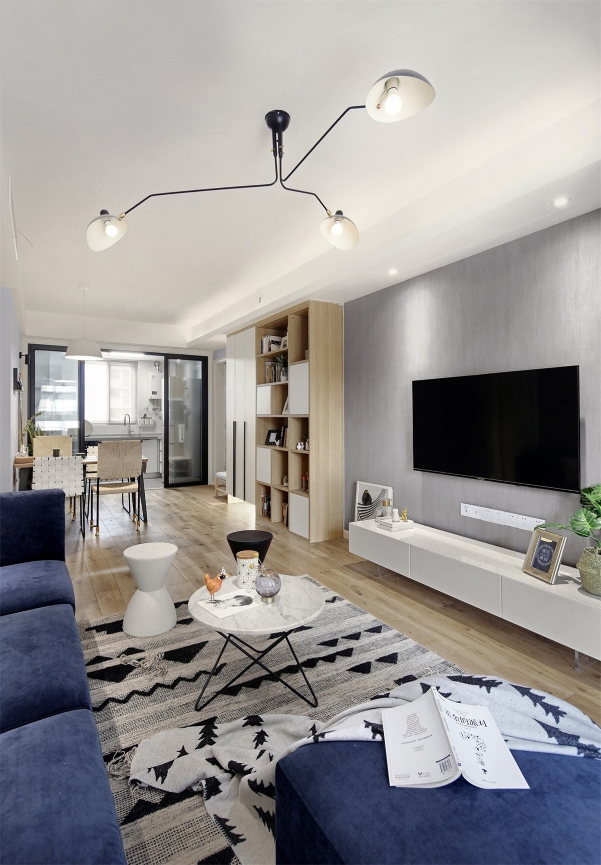 客廳以灰色墻面搭配原木色地板，簡約的背景墻設計，看起來干凈清爽，同時搭配撞色系的藍色沙發，局部亮色點綴，起到畫龍點睛的作用。
