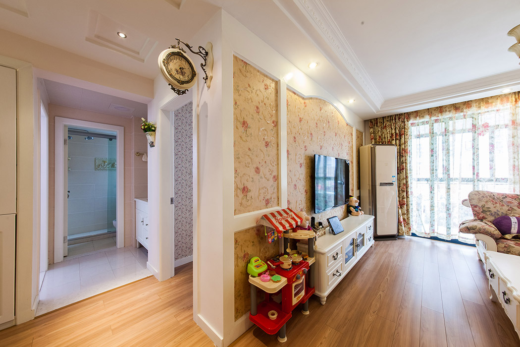 電視背景墻的造型和壁紙的選擇，加上掛壁式鐘的相互搭配，彰顯了田園風格的人文氣息
