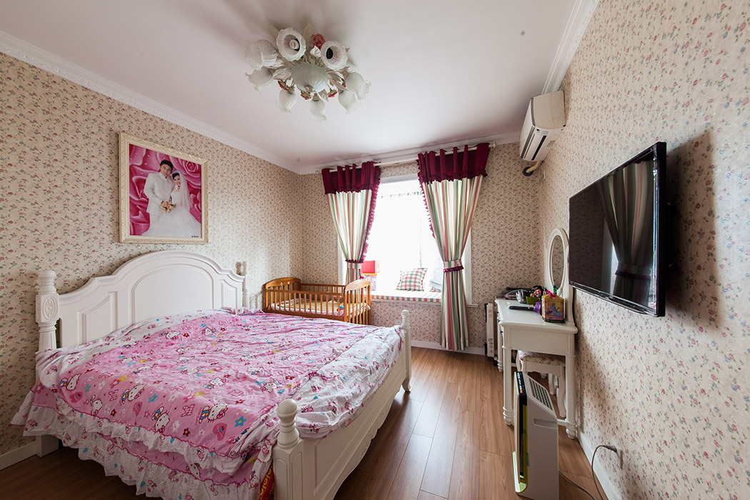 臥室延續了客廳的設計風格，小碎花的墻紙，漂亮的吊燈和窗簾，讓這里安逸的空間更加舒適
